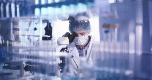 Female microbiologist studying coronavirus with microscope. Fighting with pandemic